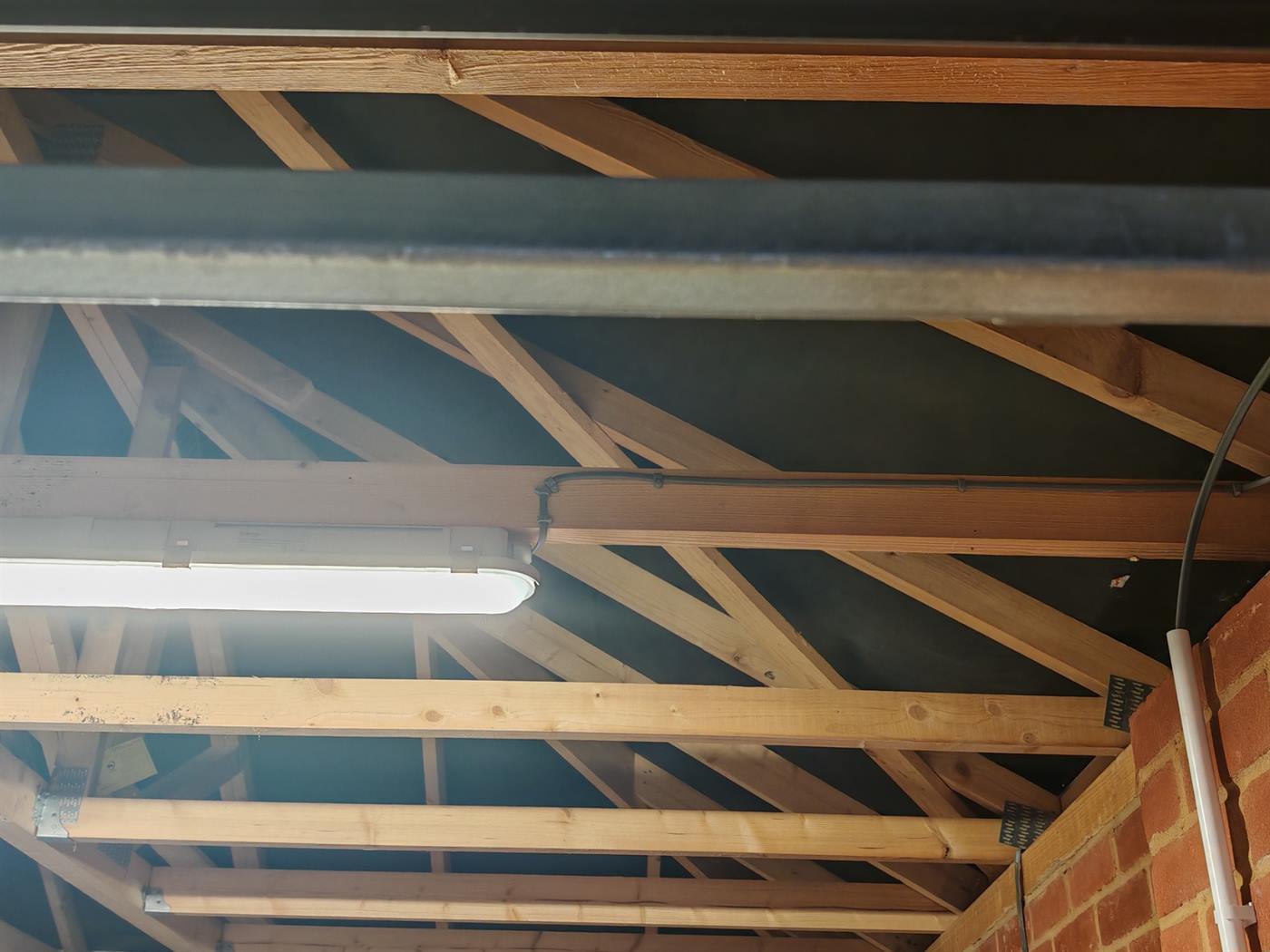 Cable clipped neatly along a timber beam feeding a garage strip light