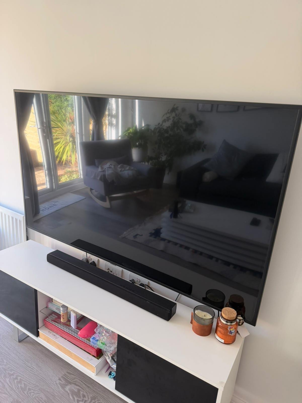 A 72-inch television mounted on a living room wall in Oxfordshire, sitting flat against the wall above a media unit