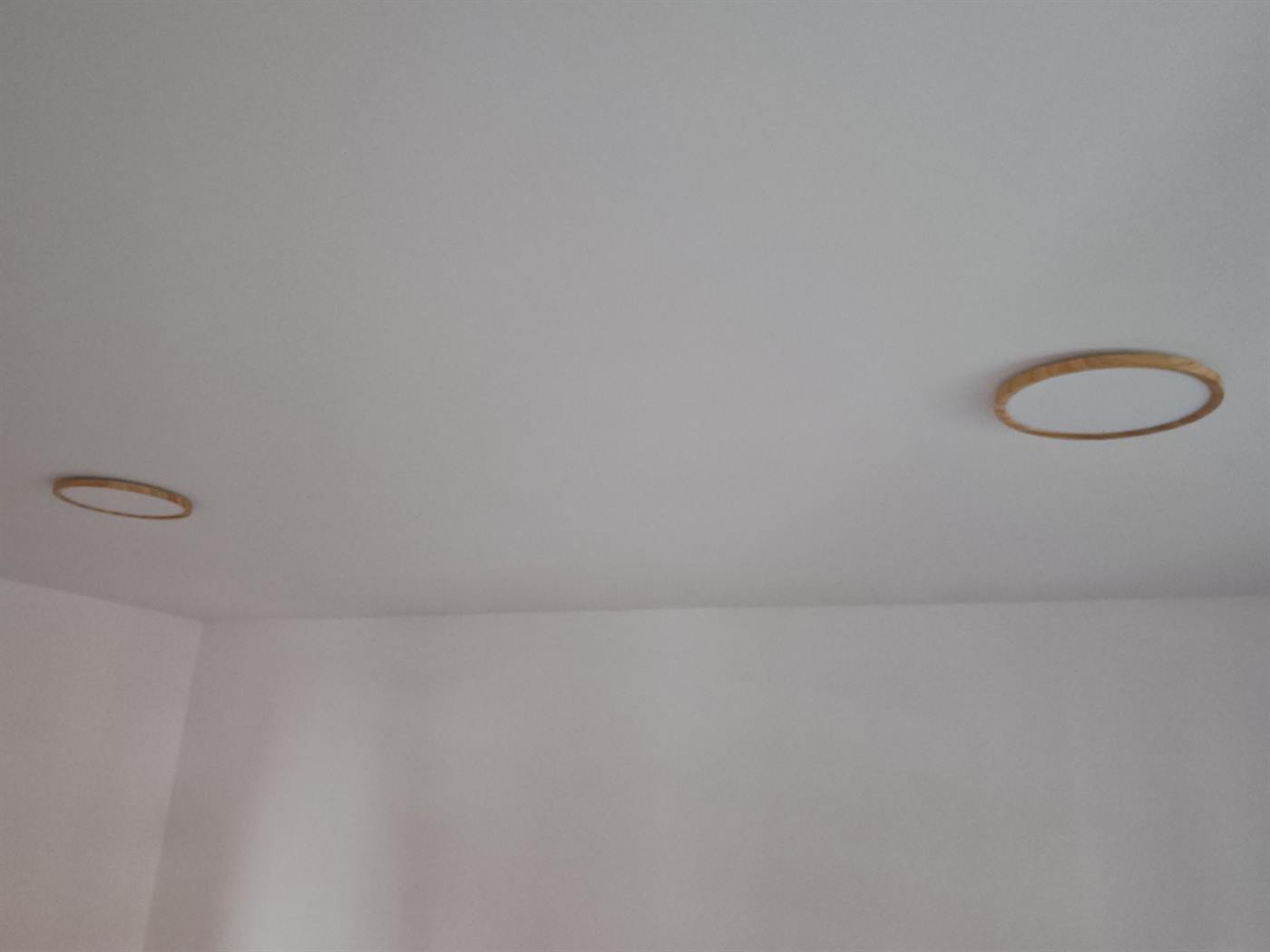 A pair of oak-rimmed ceiling lights fitted in line across a room ceiling